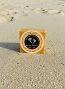 Kojic Acid + Manuka Honey + Turmeric Dark Spot Soap on sandy beach background, brightening skincare product.